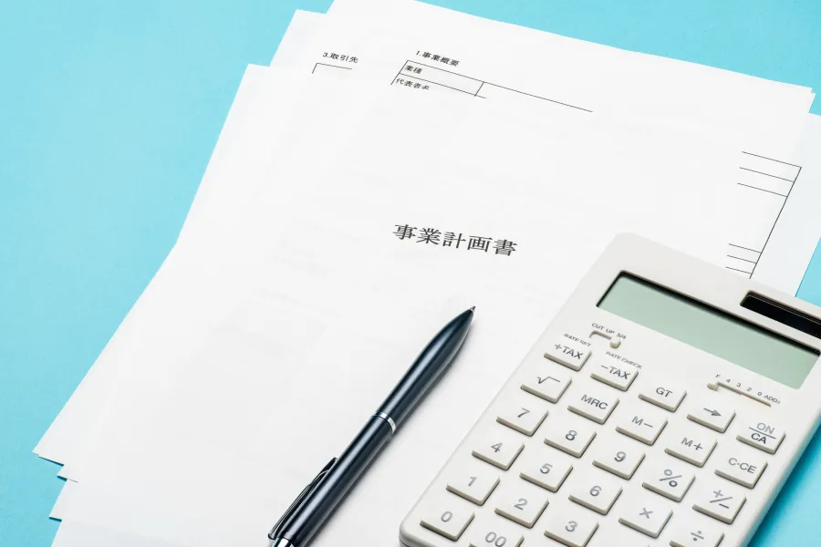 事業計画書と電卓。事業整理・再建をイメージした写真
