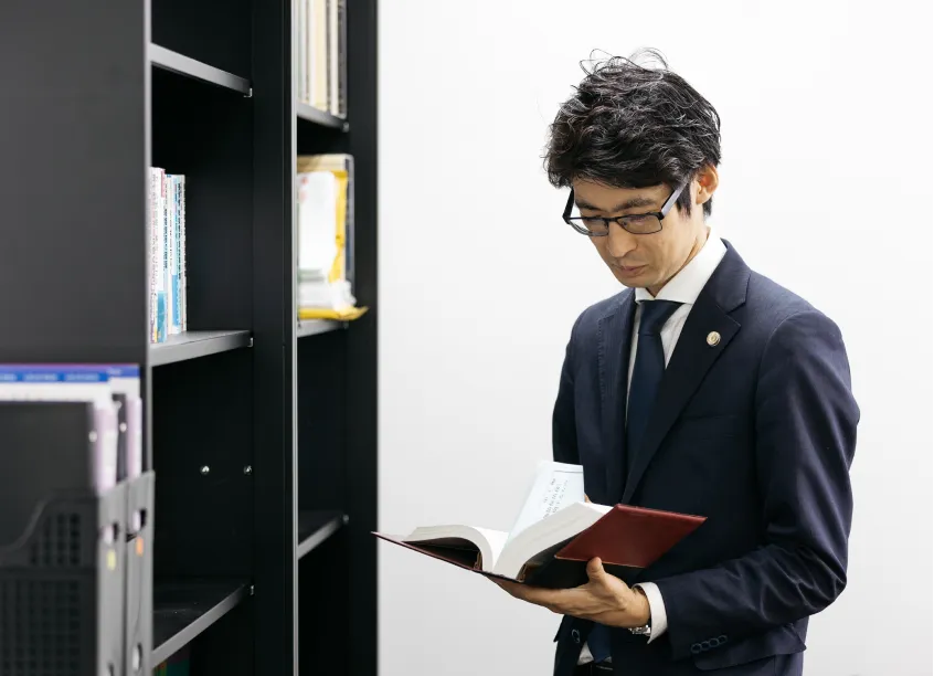 法律事務所S 座間・相模原南オフィスで遺産相続の法律書を確認する谷樹人弁護士